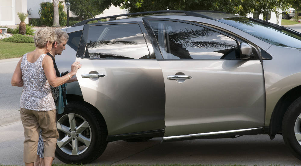 A volunteer helping a rider into a car